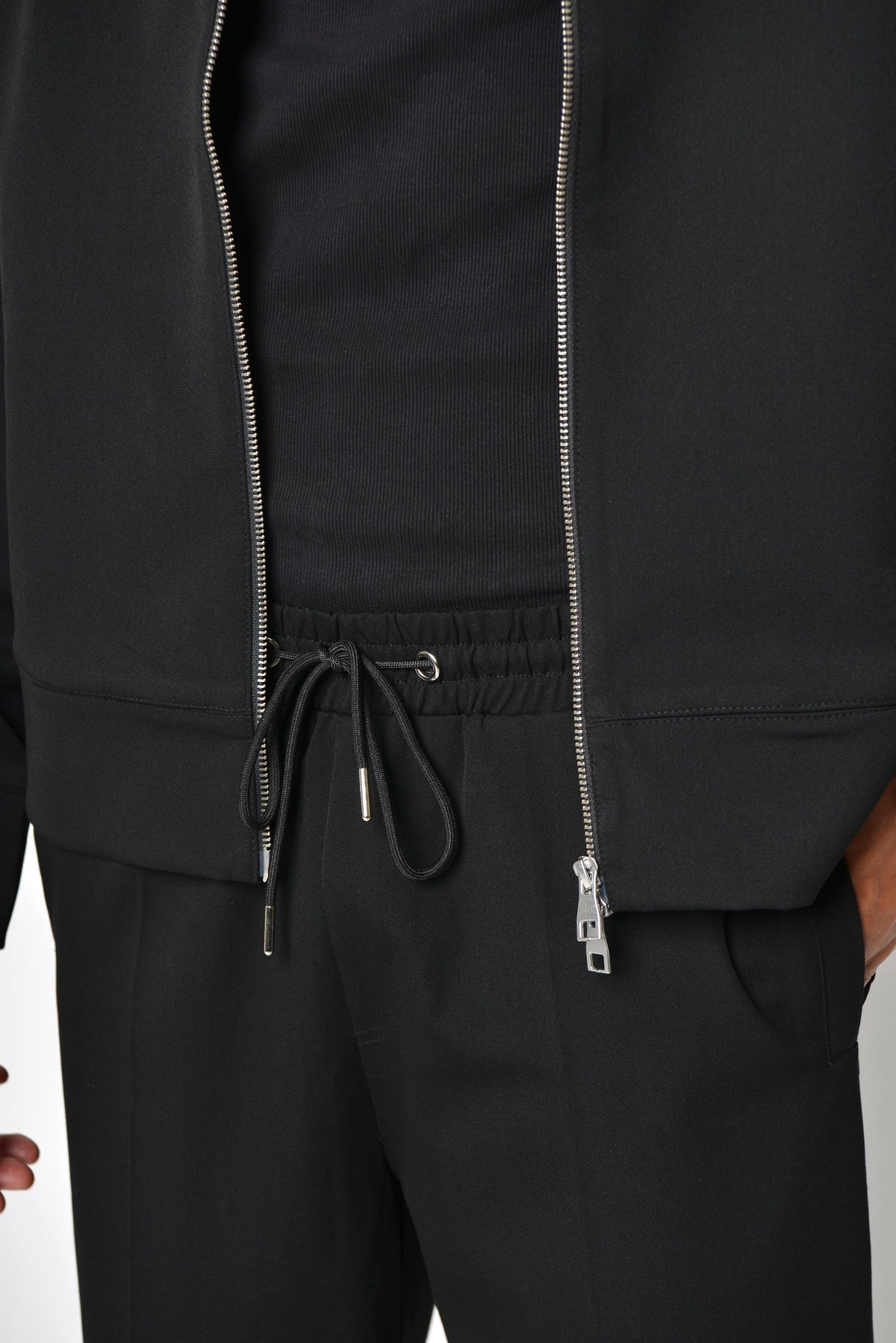 Drawstring waistband of the Tailored Straight-Leg Trouser beneath the open jacket zip